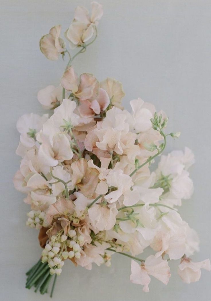 a bunch of flowers that are sitting on a table in front of a white wall