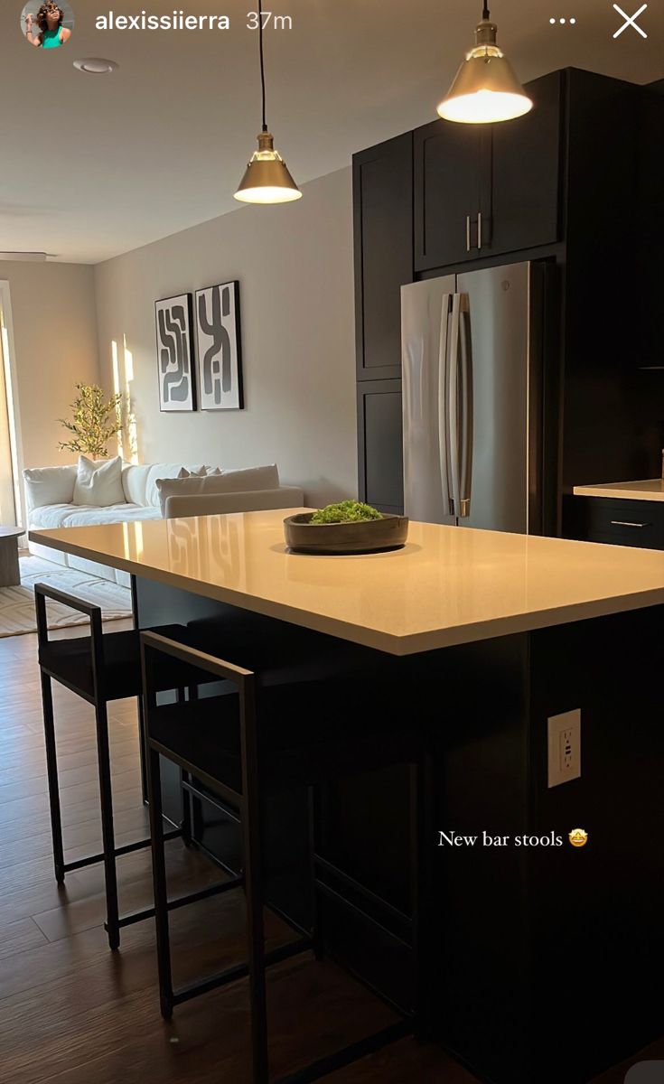 a kitchen with black cabinets and an island in front of the stove, refrigerator and sink