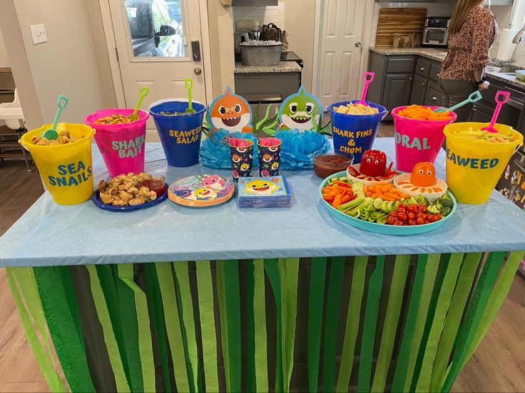 a table topped with lots of food and cups filled with different types of foods on top of it