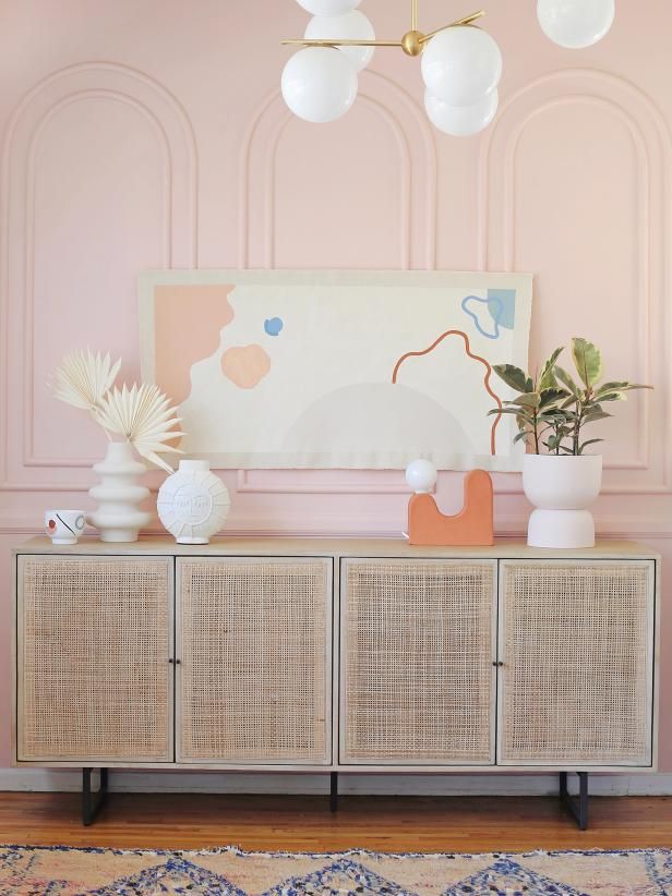 a living room with pink walls and white wicker sideboard in front of it