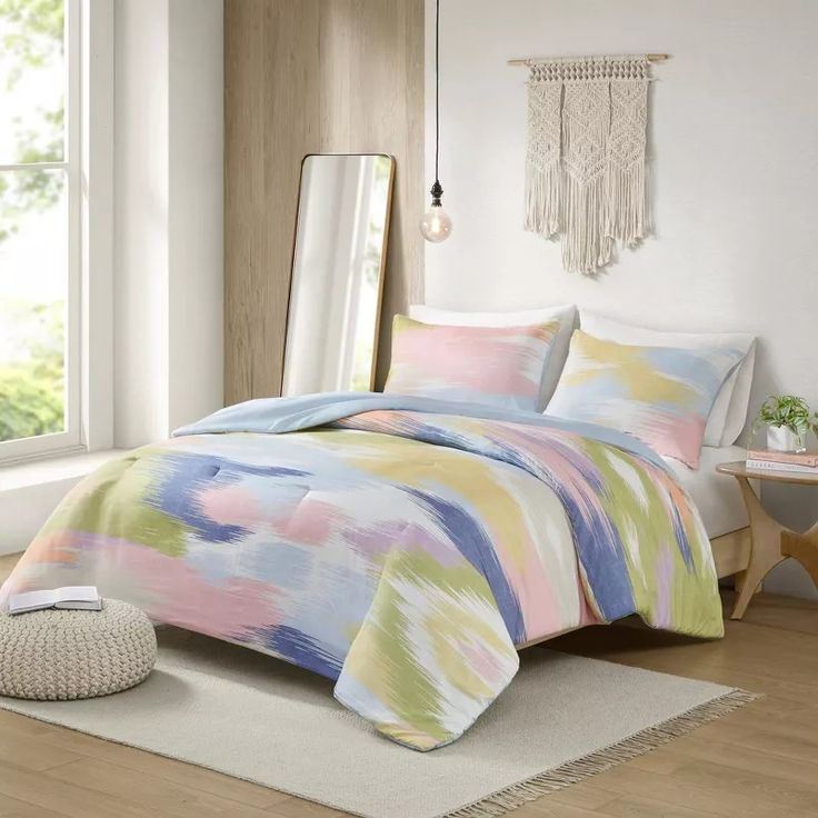 a bed in a room with a colorful comforter and pillows on the floor next to a window