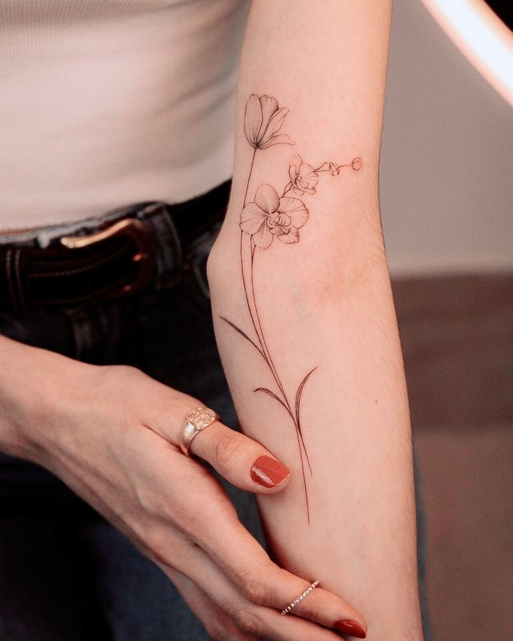 a woman's arm with a flower tattoo on the left side of her hand