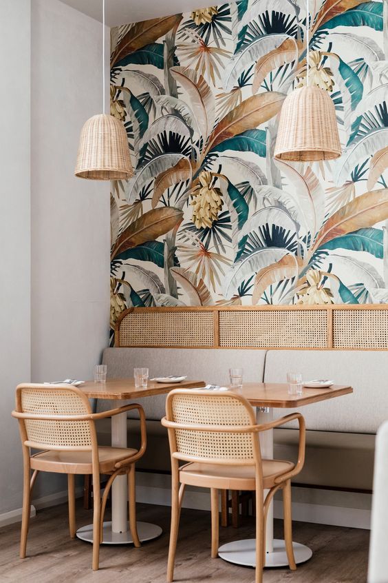 the interior of a restaurant with tropical wallpaper and rattan chairs, tables and lamps