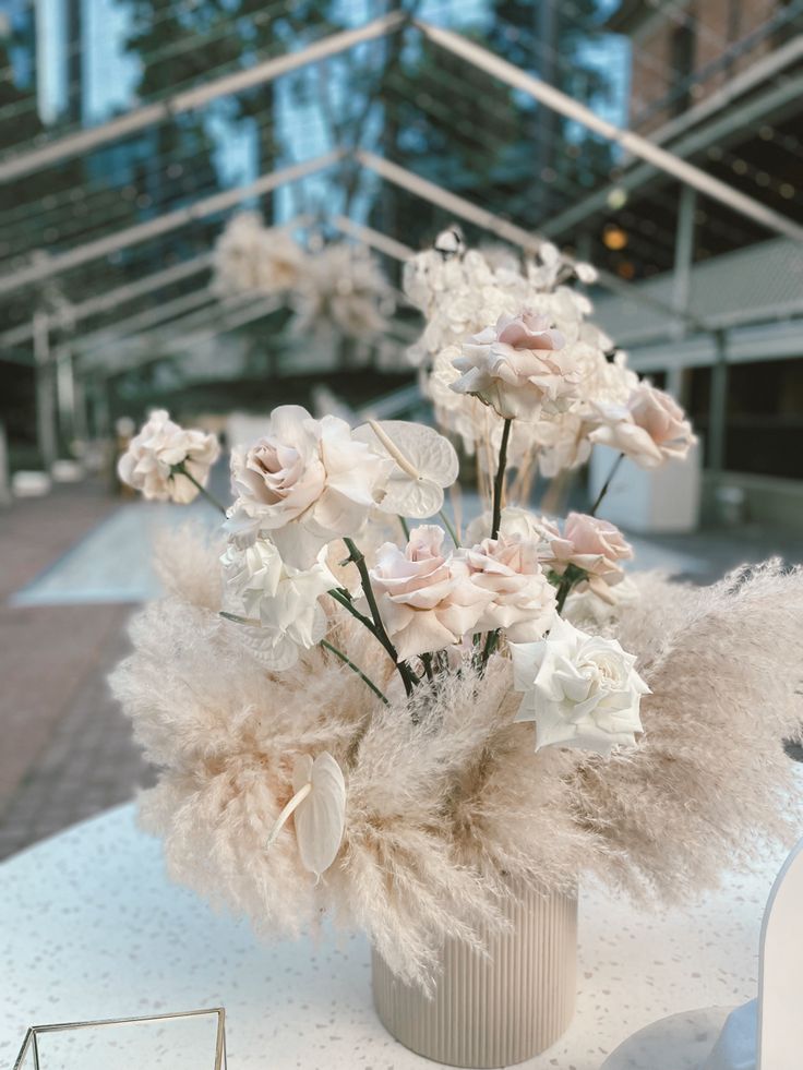 a vase filled with lots of flowers on top of a white cloth covered tablecloth