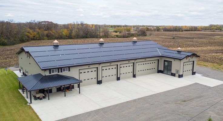 an aerial view of a large building with a metal roof and two garages in the background