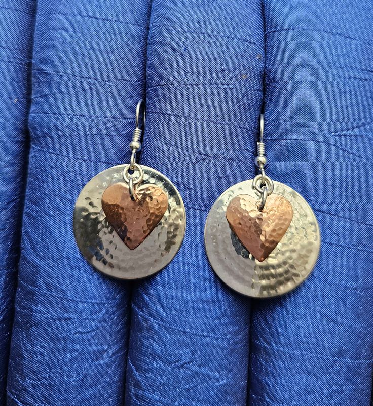 Hammered copper hearts over a one inch hammered sterling silver disc on a sterling ear wire. My unique hammering technique domes them a little and hardens the metal a little so they hold their shape well.