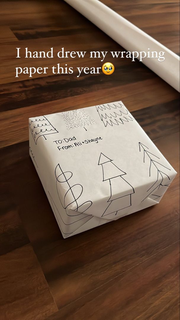 a white gift box sitting on top of a wooden floor next to a roll of paper