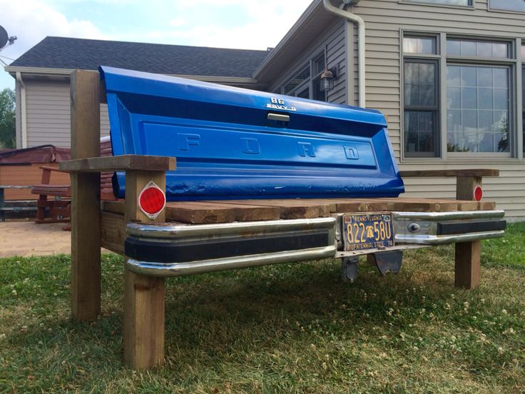 the back end of a blue pickup truck parked in front of a house with a license plate on it