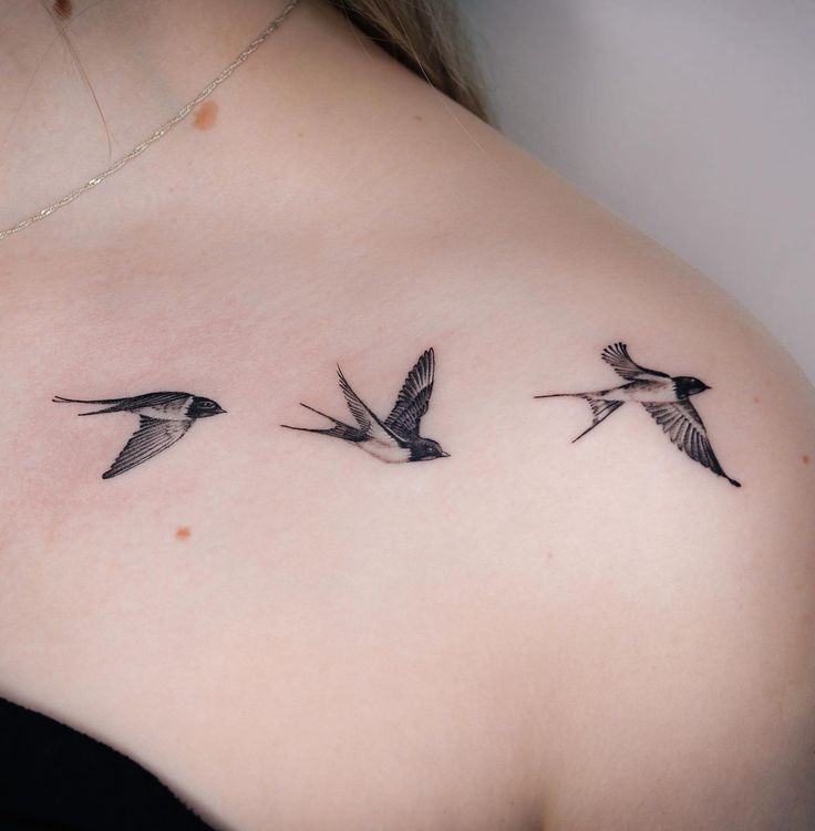 three birds flying in the air on top of a woman's back shoulder tattoo