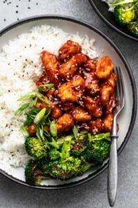 a bowl filled with rice and broccoli covered in sauce next to a fork