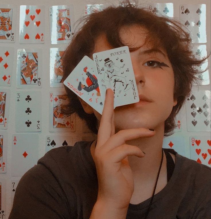 a person holding up playing cards in front of their face