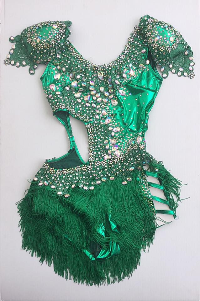 a green dress with sequins and feathers on the bottom is displayed in front of a white background