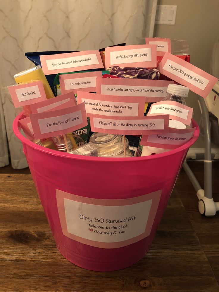 a pink bucket filled with lots of notes and candy bar wrappers on top of a wooden floor