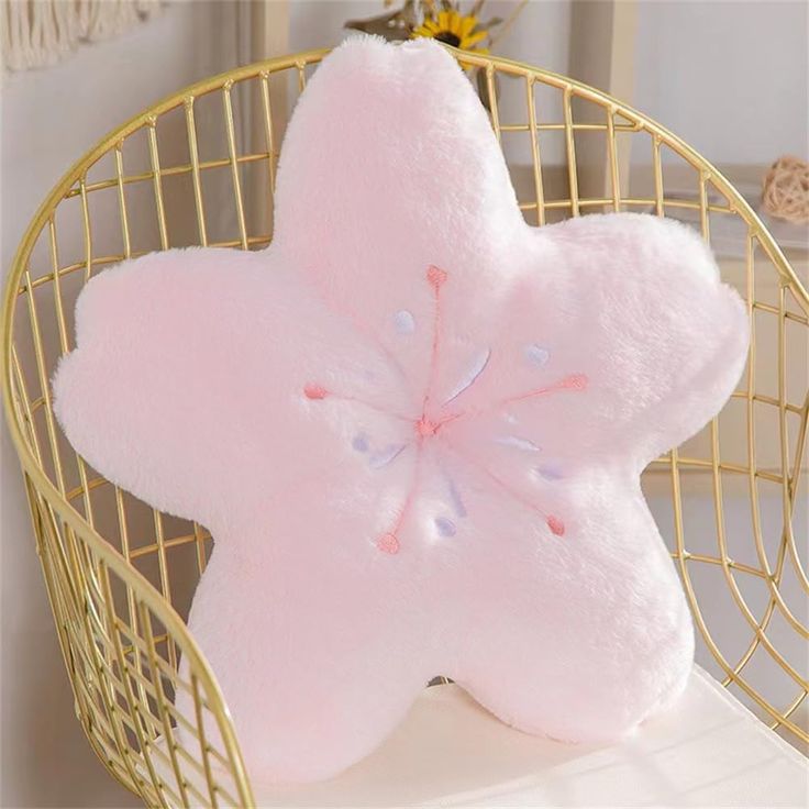 a pink star shaped pillow sitting on top of a white table next to a gold basket