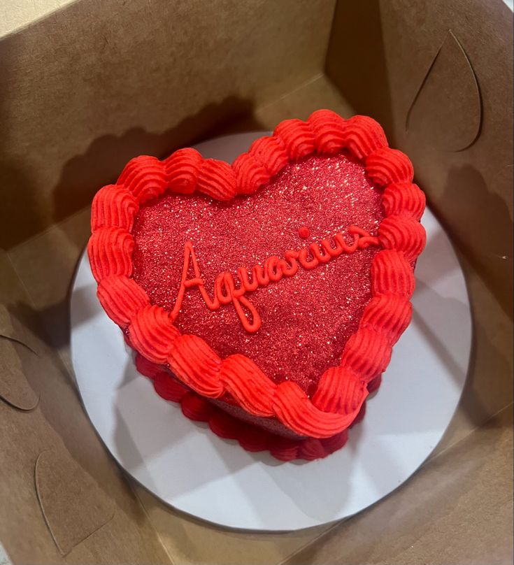 a red heart shaped cake with the word agressine on it in a box