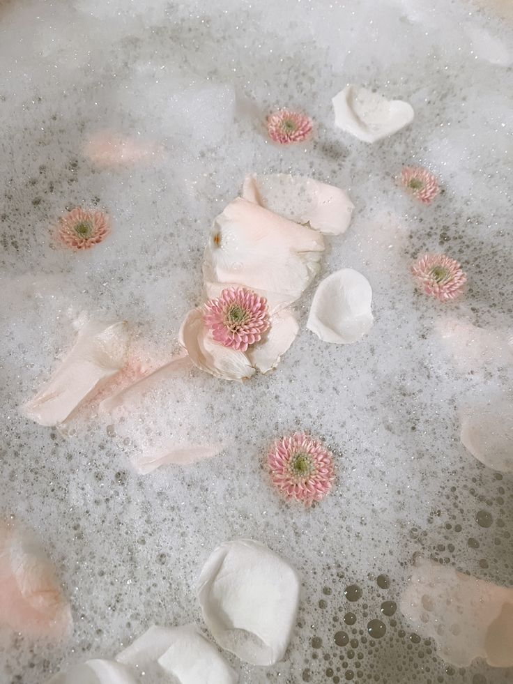 pink flowers are floating in a bubbley bath