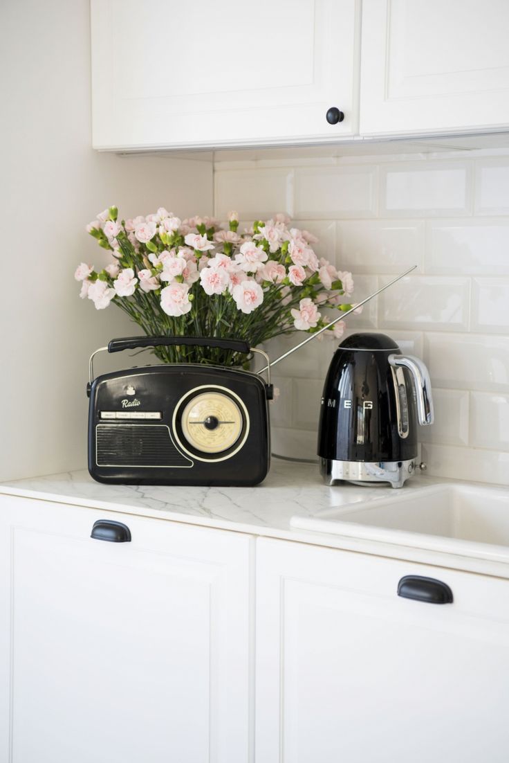 a black toaster sitting on top of a white counter next to pink and white flowers