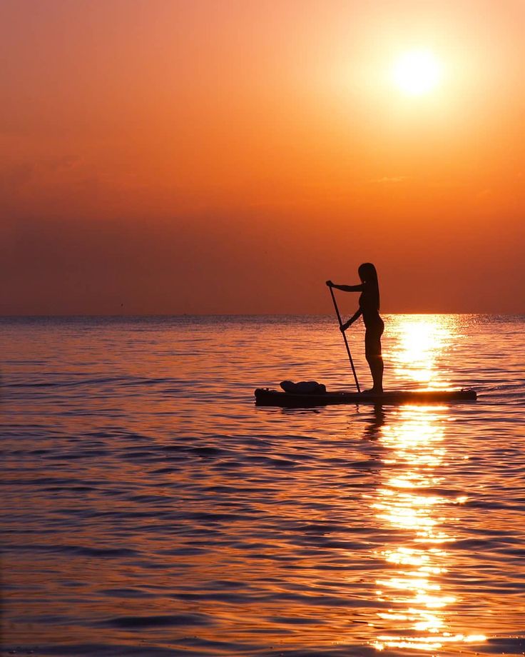 a person on a paddle board in the water at sunset or dawn with an oar