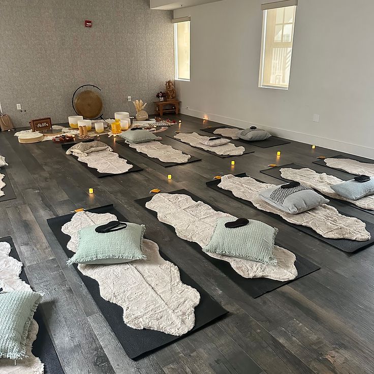 yoga mats are laid out on the floor in an empty room with candles lit up