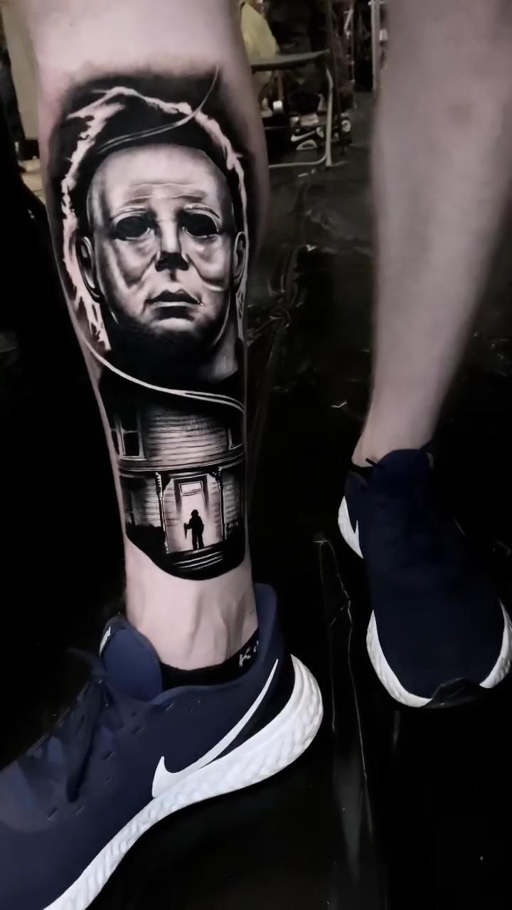 a man's leg with a black and white tattoo on it, which has an image of a person standing in front of him