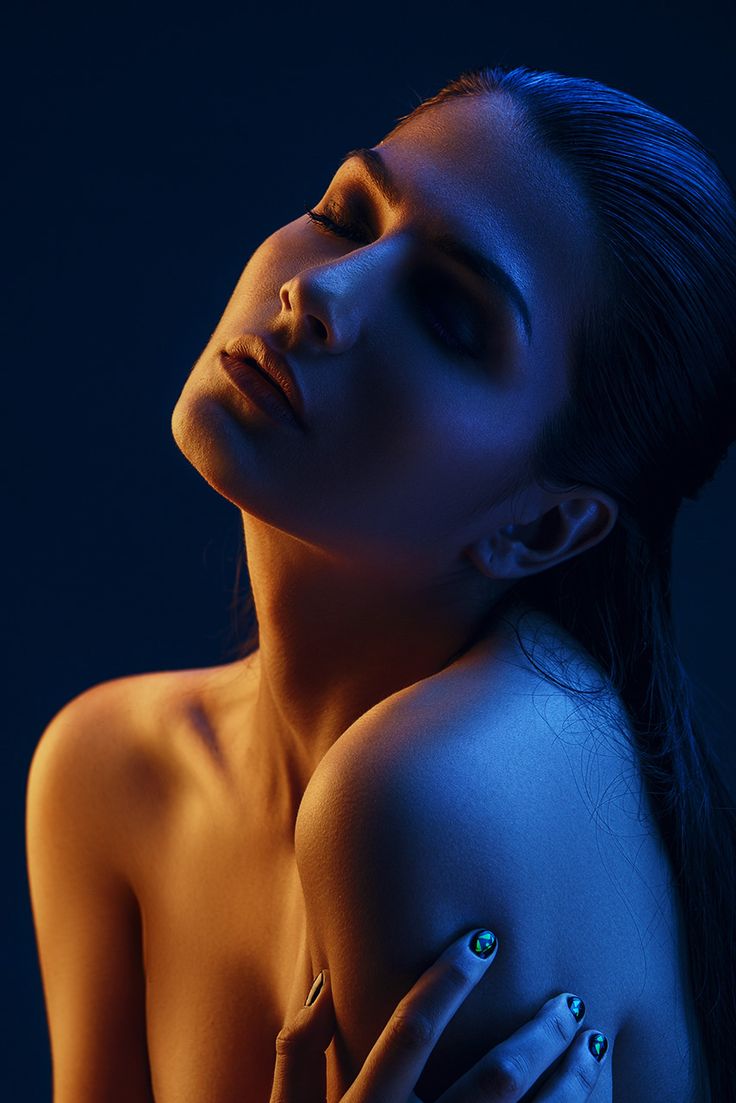 a naked woman with blue lights on her face and arm, posing for the camera