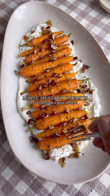 a person is holding a fork over a plate of carrots and whipped cream on a checkered table cloth