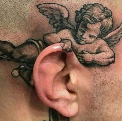 a man with tattoos on his chest has an ear piercing in the shape of a cherub