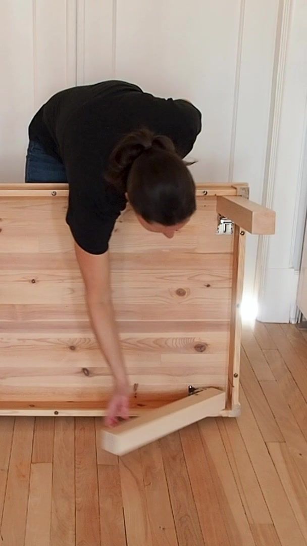 a woman bending over on top of a bed frame with wood planks in it