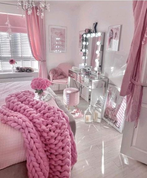 a bedroom decorated in pink and white with chandelier, bed, dresser, mirror and chair