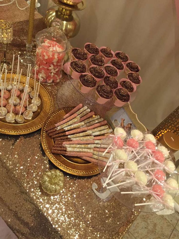 a table topped with lots of desserts and candies on top of gold plates