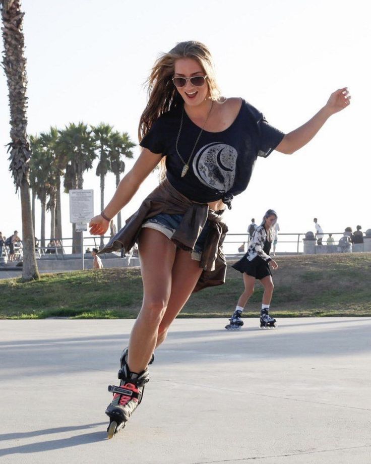 a woman riding a skateboard down the side of a road next to palm trees