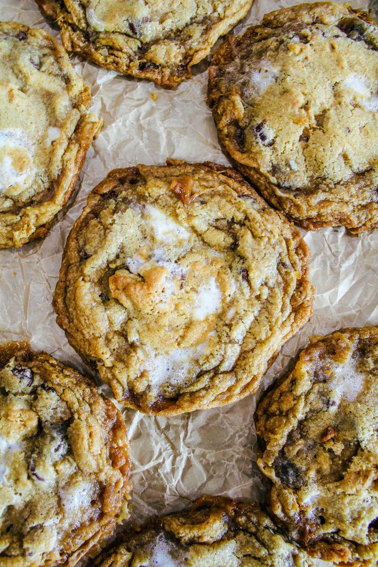 chocolate chip cookies with white icing and crumbled on top sitting on wax paper