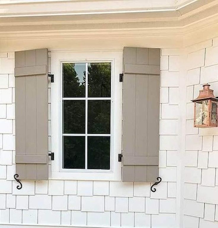 two windows with shutters on the side of a house