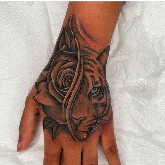 a hand with a tiger and rose tattoo on it