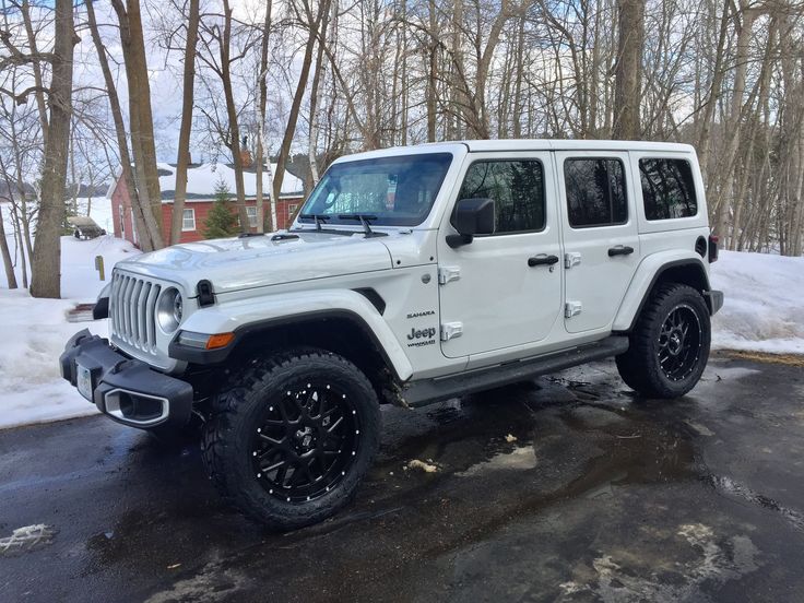 a white jeep parked on the side of a road in front of some trees and snow