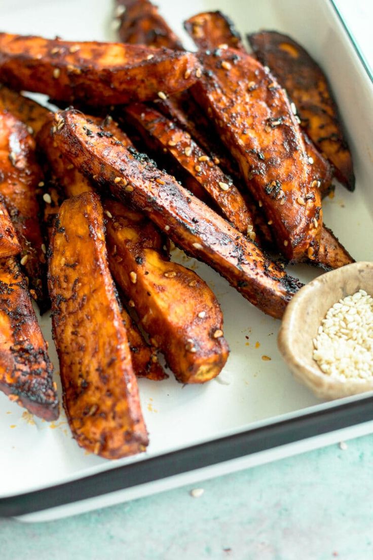 some chicken wings are on a plate next to a small bowl of rice and seasoning