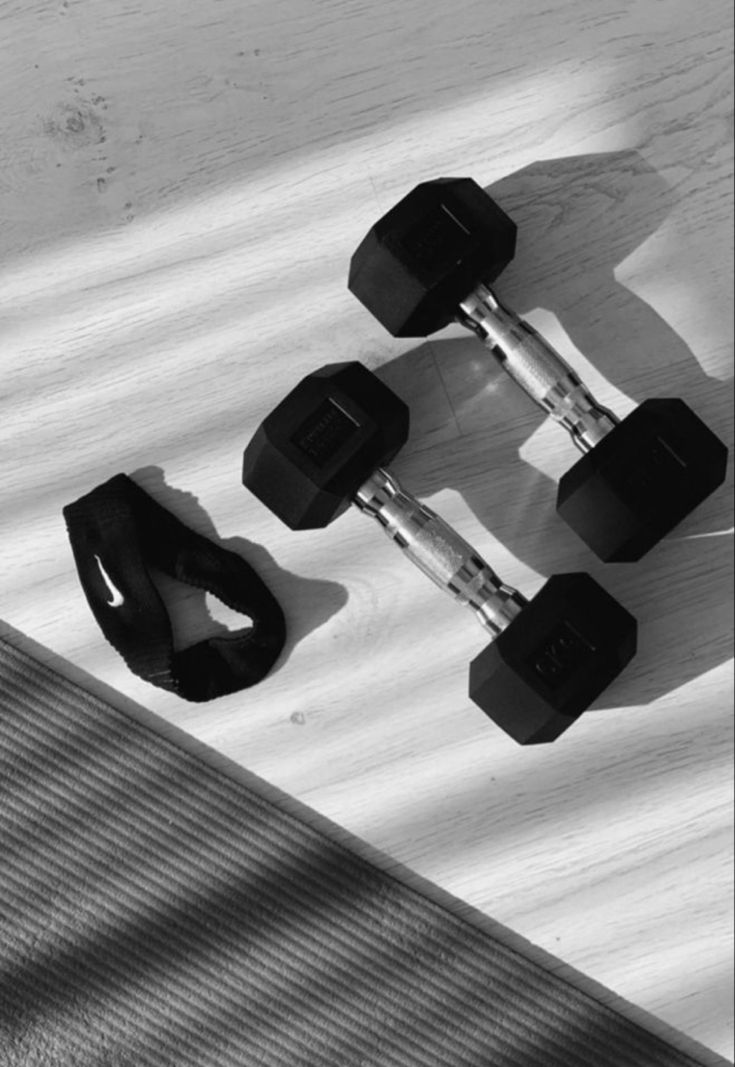 two black dumbbells sitting on top of a skateboard