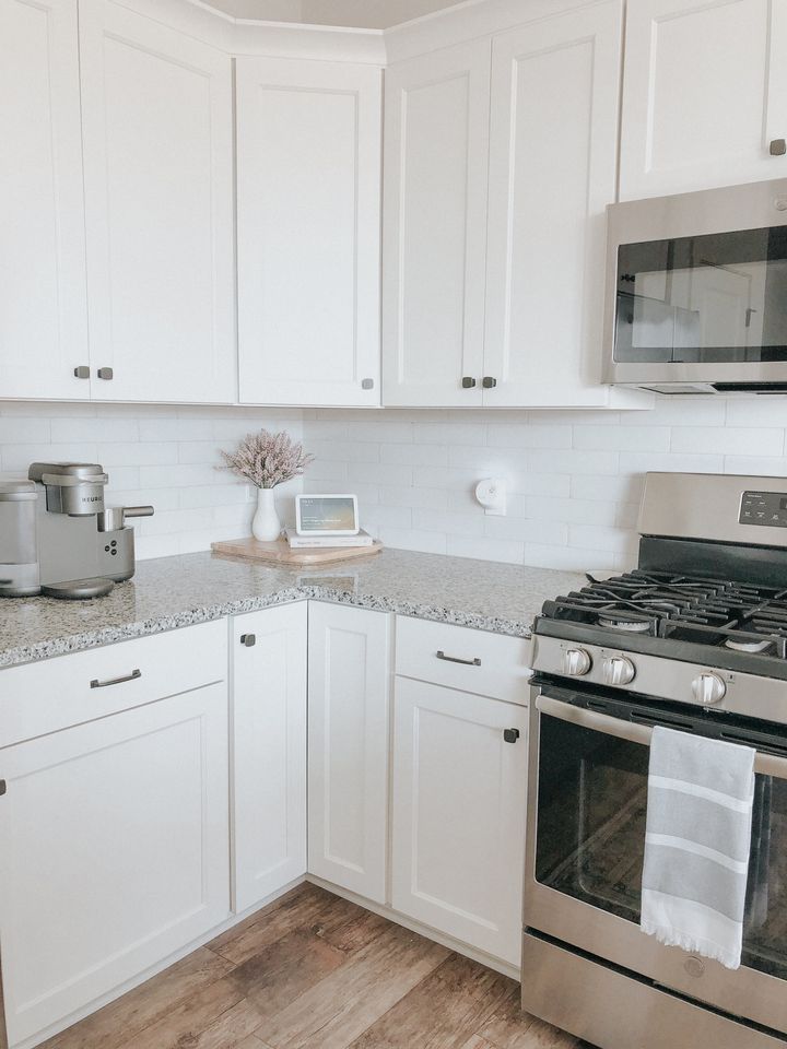 a kitchen with white cabinets and stainless steel stove top oven in the middle of it