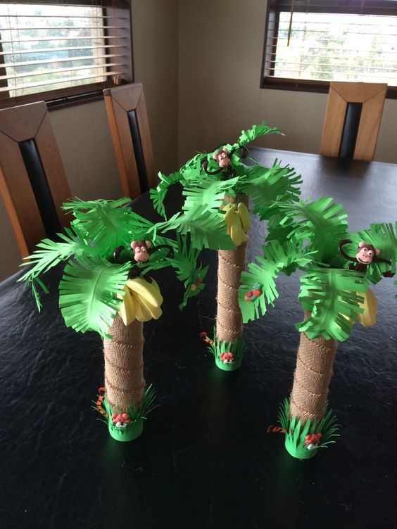 three palm trees made out of toilet paper sitting on a black table with windows in the background