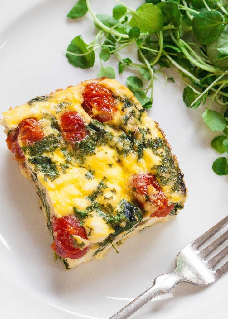 spinach, tomatoes and feta frittata squares on a white plate with text overlay