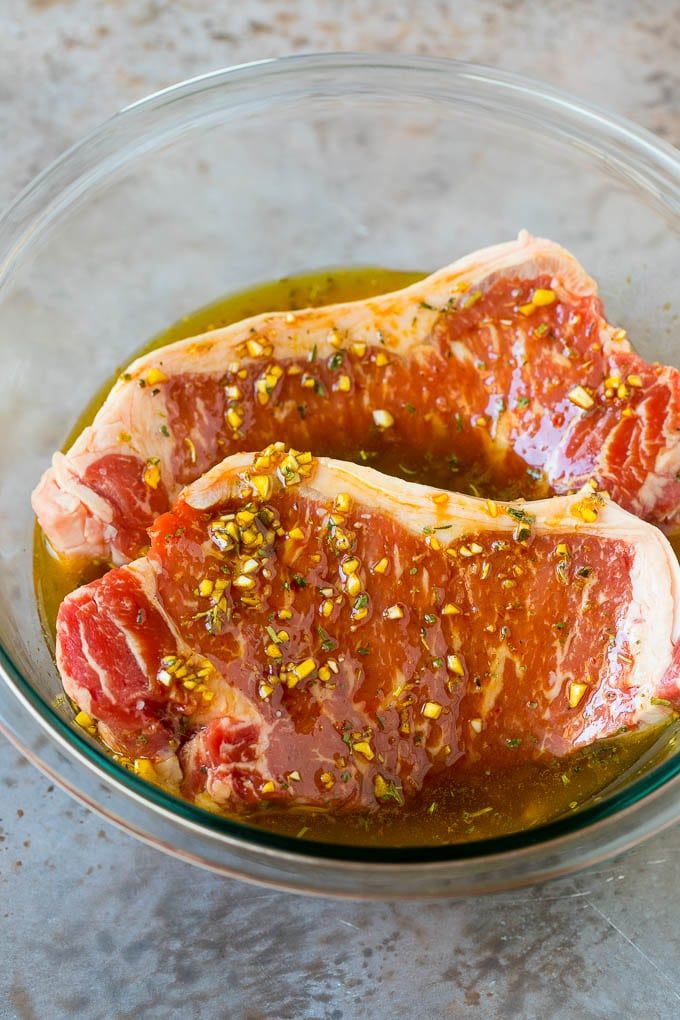 two raw meats in a glass bowl with seasoning and pepper sprinkles