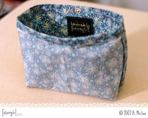 a close up of a small blue flowered bag on a table with a name tag