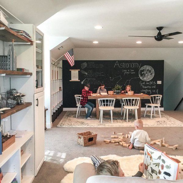 two children sitting on the floor in front of a chalkboard wall with an astronaut written on it