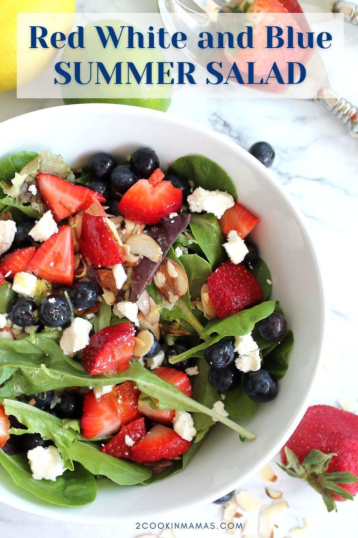 a white bowl filled with spinach, strawberries and blueberries on top of a marble counter