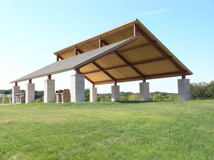 an outdoor covered structure in the middle of a field with columns and pillars on each side