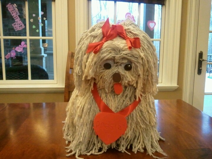 a dog made out of toilet paper sitting on top of a wooden table next to a window