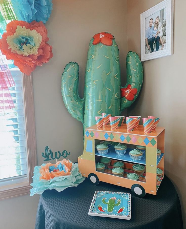 a table topped with cupcakes and an inflatable cactus on top of it