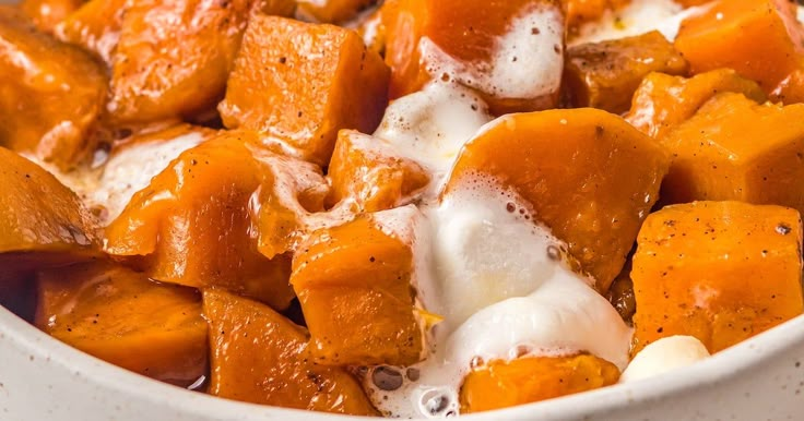 a white bowl filled with sweet potatoes and marshmallows covered in sour cream