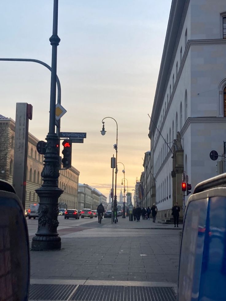 an empty city street with traffic lights and people walking on the sidewalk in the distance