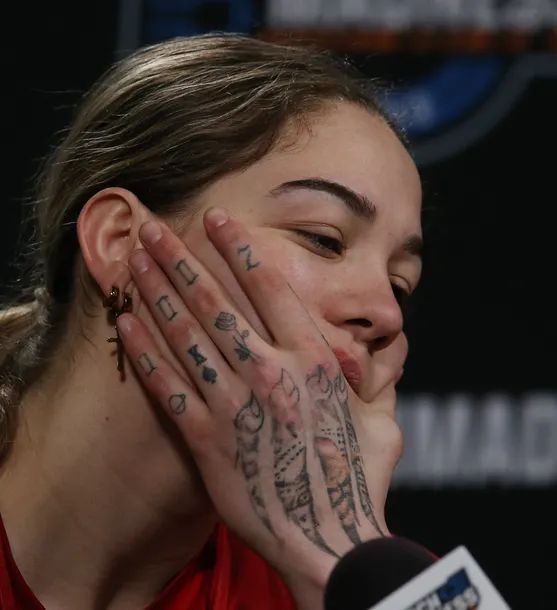 a woman with tattoos covering her face while holding her hands up to her face and looking at the camera